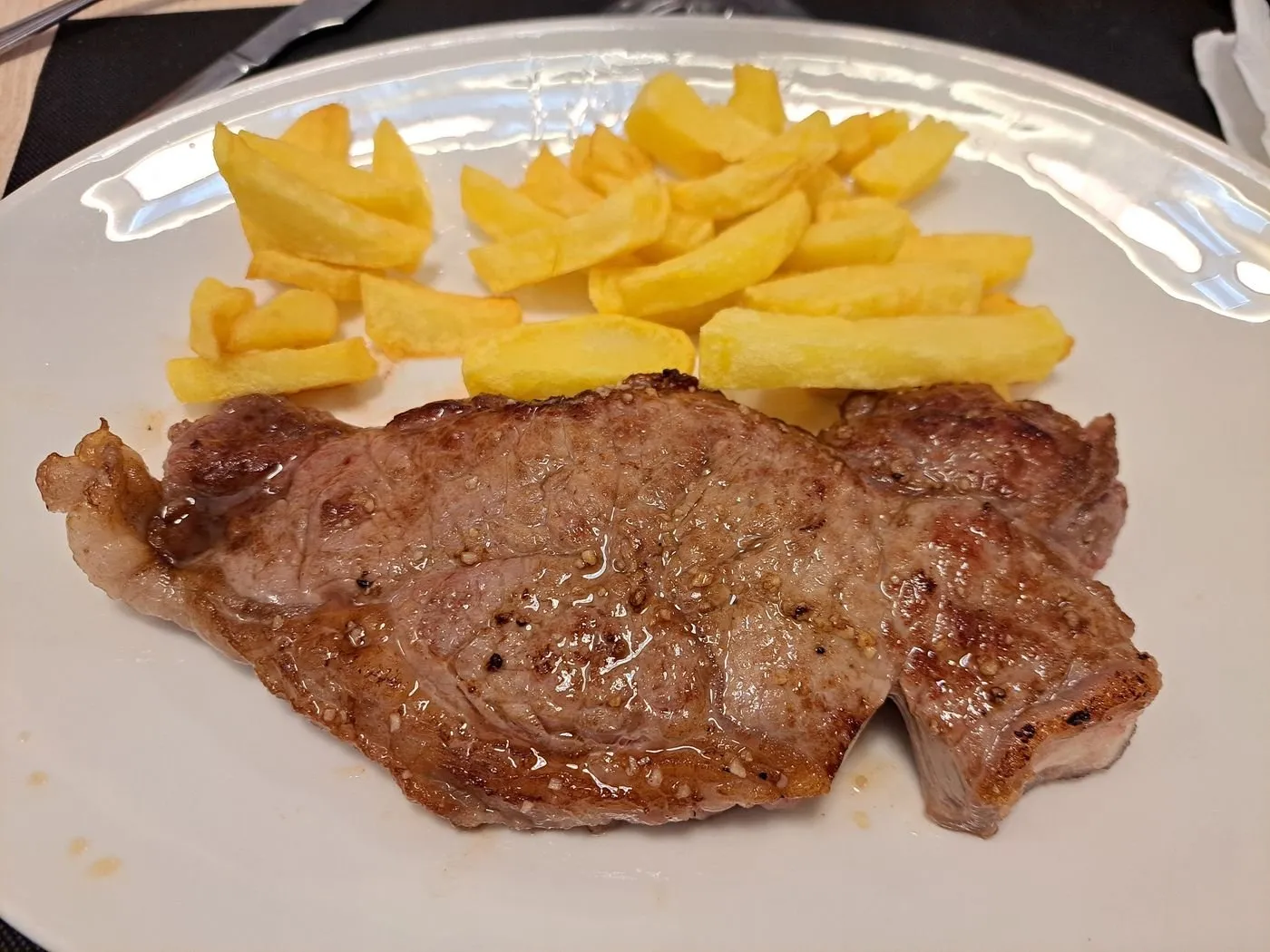 Entrecot a la plancha con patatas fritas en un plato blanco