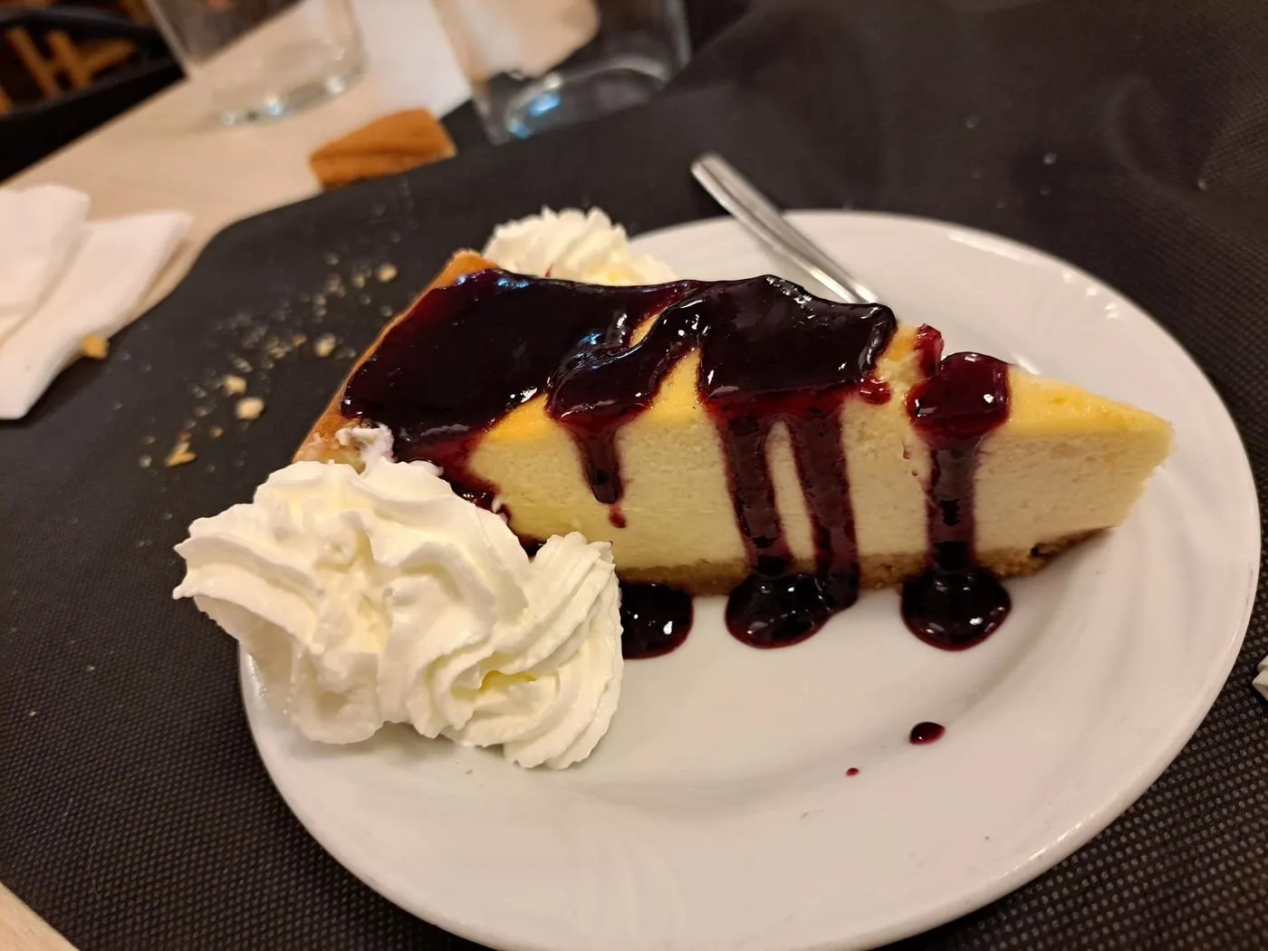 Porción de tarta de queso con mermelada de frutos rojos y nata montada